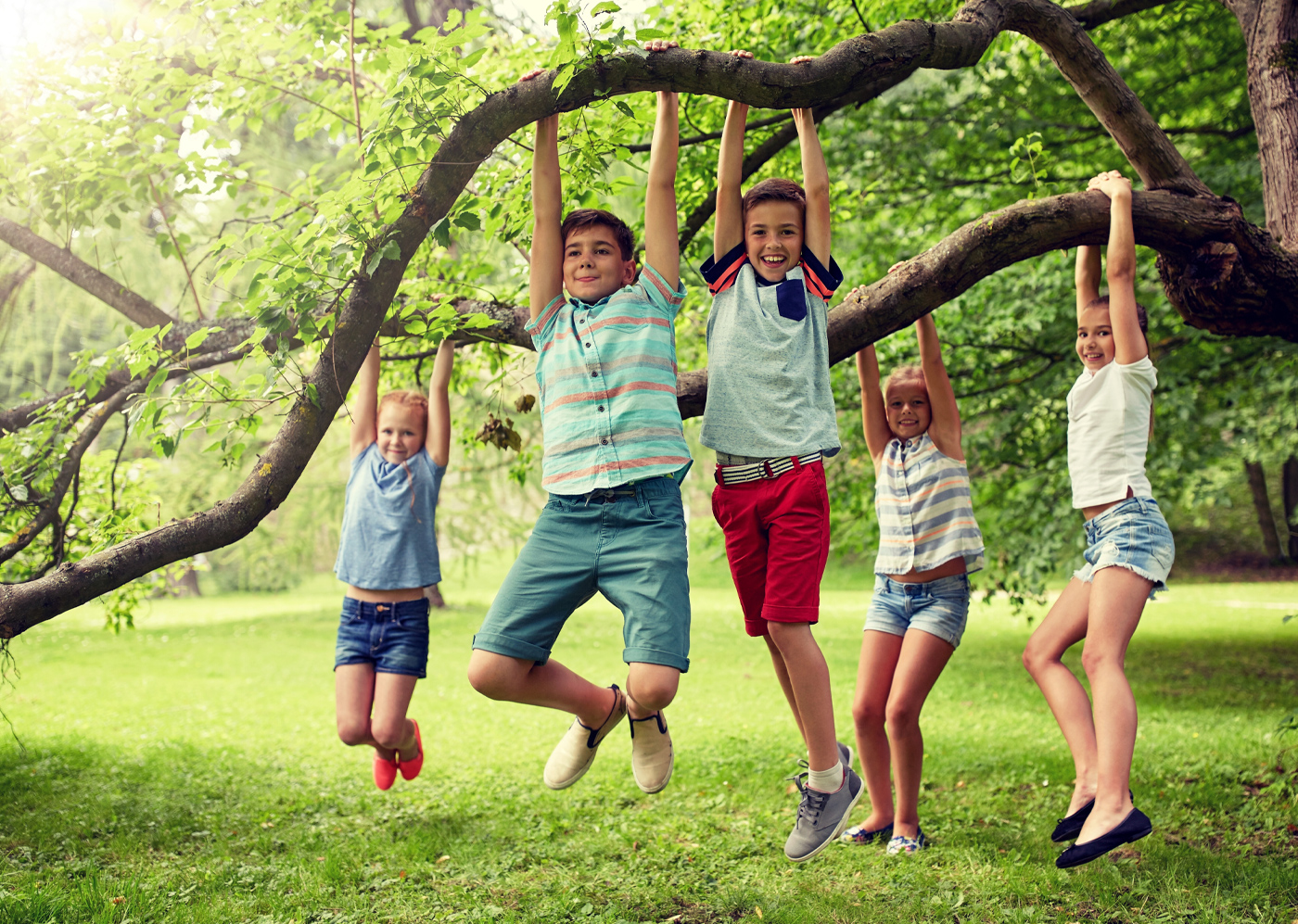 Spielende Kinder hängen lachend am Baum