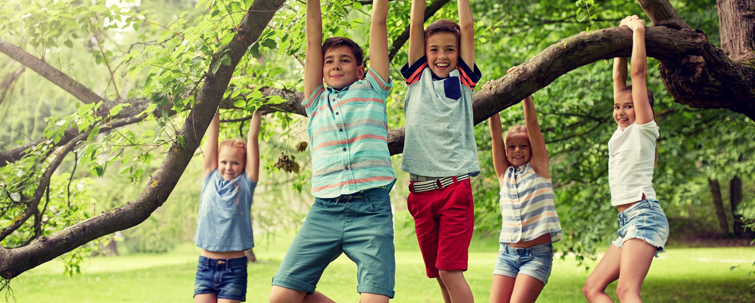 Spielende Kinder hängen lachend am Baum